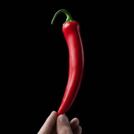 Hot red pepper in the hand. Black background